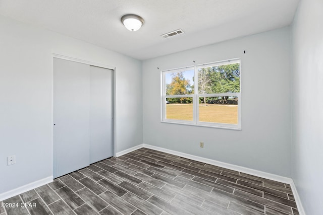 unfurnished bedroom featuring a closet, dark hardwood / wood-style flooring, and a textured ceiling