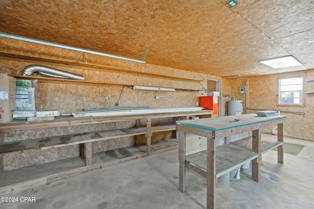 miscellaneous room with a workshop area, concrete floors, and water heater