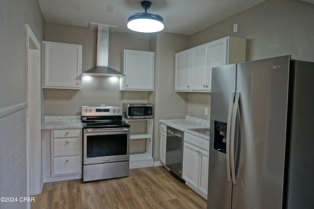 kitchen with white cabinets, wall chimney range hood, stainless steel appliances, and hardwood / wood-style flooring