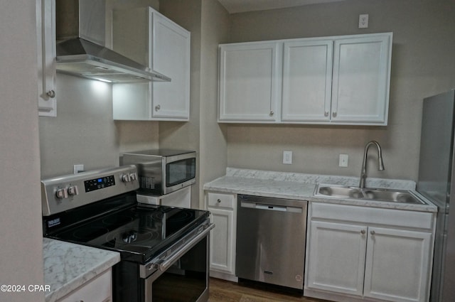 kitchen featuring white cabinets, sink, stainless steel appliances, and wall chimney range hood