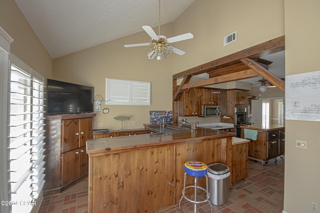 kitchen featuring kitchen peninsula, a kitchen bar, stainless steel appliances, ceiling fan, and high vaulted ceiling