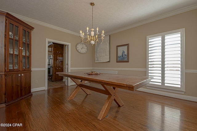 unfurnished dining area featuring a textured ceiling, light hardwood / wood-style floors, an inviting chandelier, and crown molding