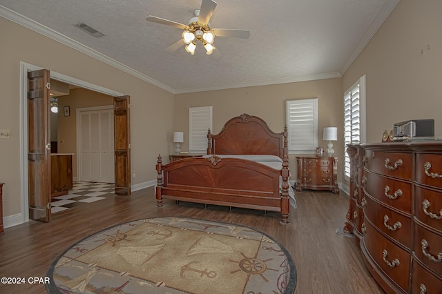 bedroom with dark hardwood / wood-style floors, ceiling fan, ornamental molding, and a textured ceiling