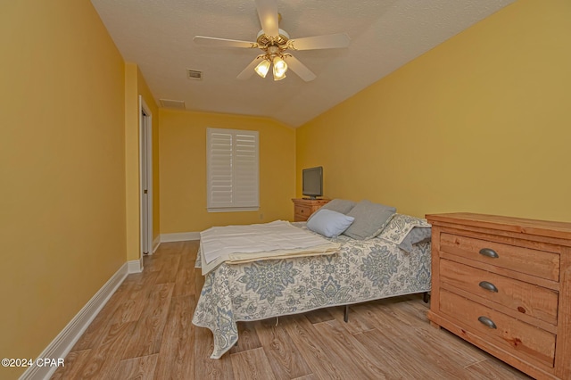 bedroom featuring a textured ceiling, light hardwood / wood-style flooring, ceiling fan, and lofted ceiling