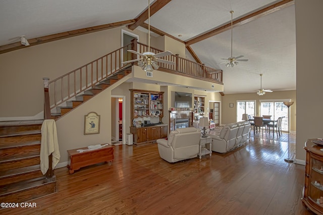 living room featuring beamed ceiling, ceiling fan, wood-type flooring, and high vaulted ceiling