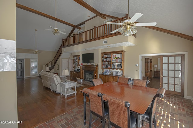 dining area featuring dark wood-type flooring, high vaulted ceiling, ceiling fan, a textured ceiling, and beamed ceiling