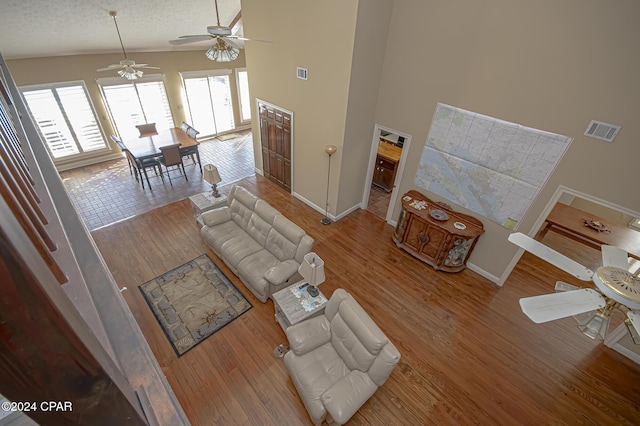 living room with wood-type flooring, a textured ceiling, high vaulted ceiling, and ceiling fan