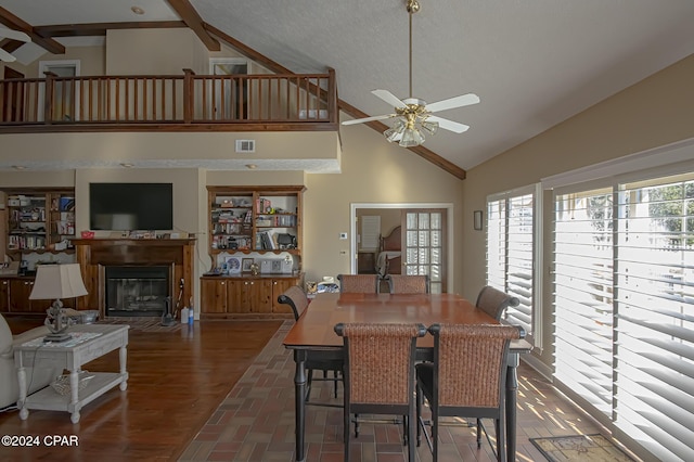 dining space featuring ceiling fan, dark hardwood / wood-style flooring, beamed ceiling, high vaulted ceiling, and a textured ceiling