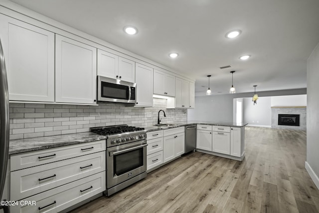 kitchen featuring white cabinetry, kitchen peninsula, pendant lighting, appliances with stainless steel finishes, and light wood-type flooring