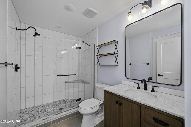 bathroom with a tile shower, vanity, and toilet