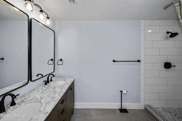 bathroom featuring a tile shower, vanity, and tile patterned floors