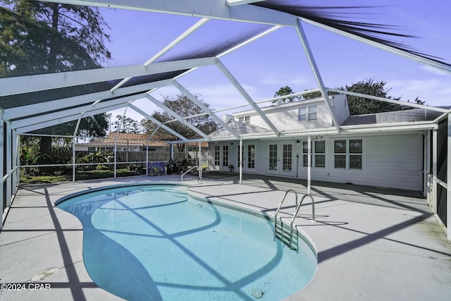 view of swimming pool featuring glass enclosure, a patio, and french doors