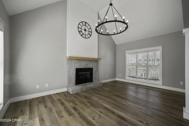 unfurnished living room featuring hardwood / wood-style floors, a chandelier, and lofted ceiling