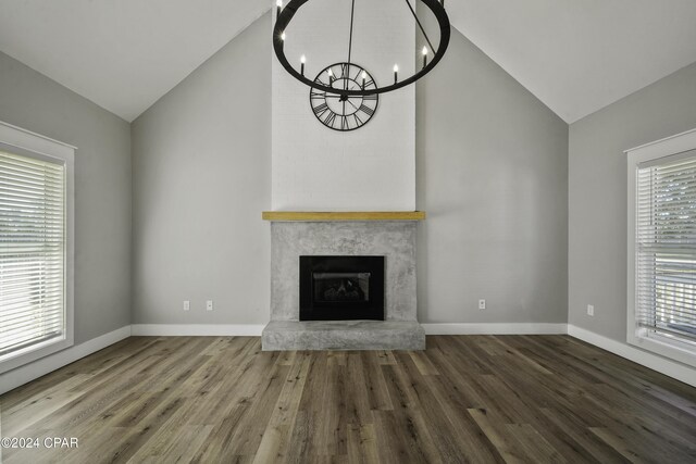 unfurnished living room with wood-type flooring, lofted ceiling, and a notable chandelier