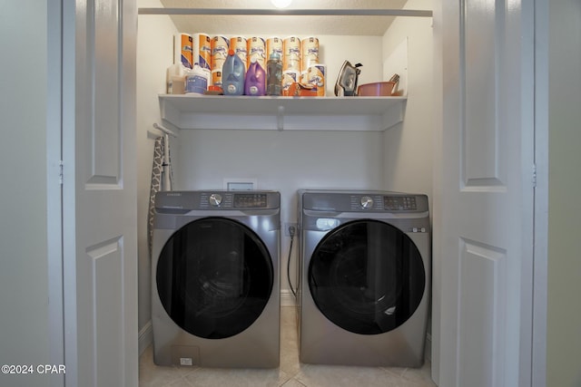 clothes washing area with washer and dryer and light tile patterned floors