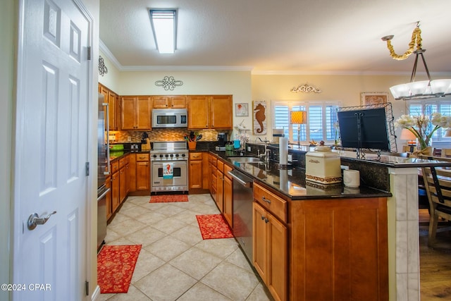 kitchen featuring kitchen peninsula, appliances with stainless steel finishes, ornamental molding, sink, and pendant lighting