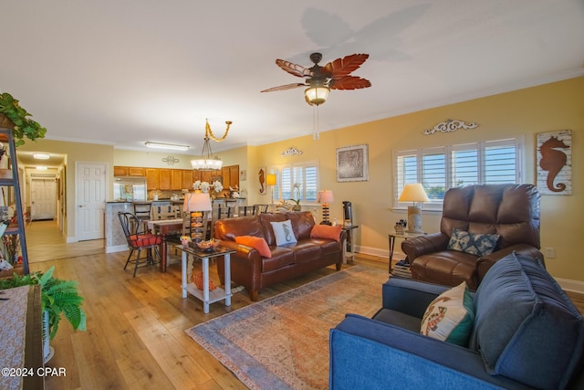 living room featuring ceiling fan with notable chandelier, light hardwood / wood-style floors, and crown molding