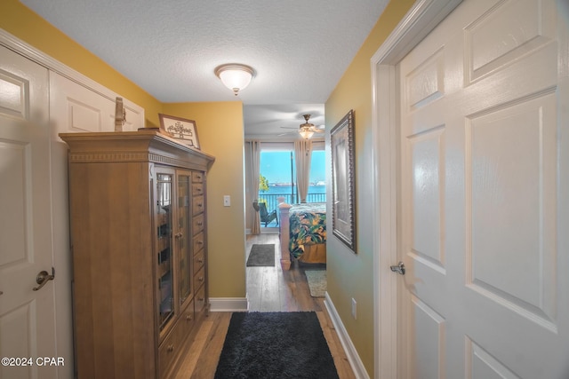 corridor with dark hardwood / wood-style floors and a textured ceiling