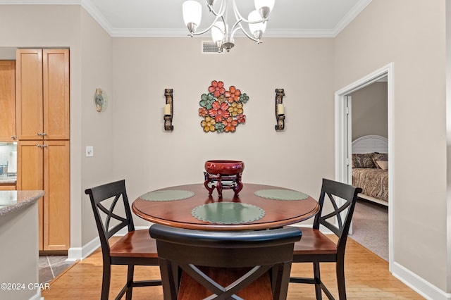 dining space with a notable chandelier, crown molding, and light hardwood / wood-style flooring