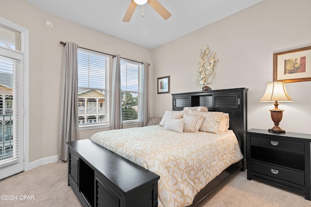 bedroom with ceiling fan, access to exterior, light carpet, and multiple windows