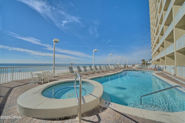 view of pool featuring a community hot tub, a water view, a patio, and a beach view