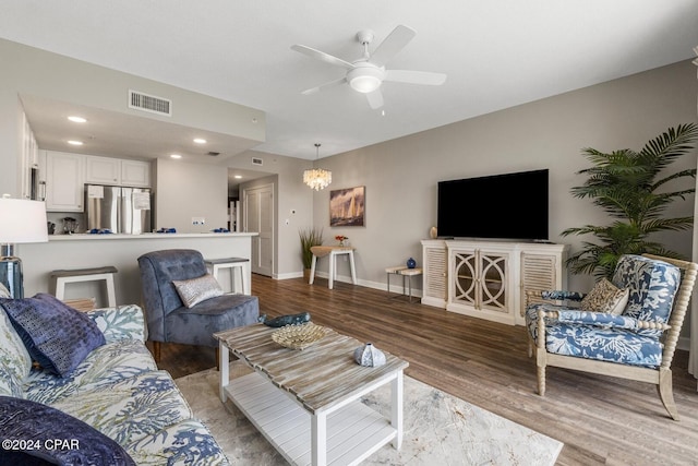 living room featuring hardwood / wood-style floors and ceiling fan with notable chandelier