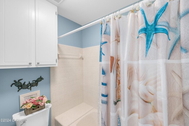 bathroom with toilet and a shower with shower curtain