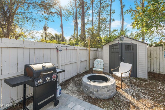 view of patio / terrace with a fire pit, a storage unit, and a grill