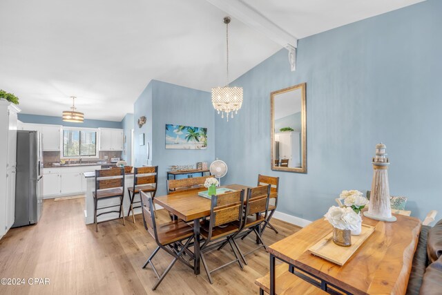 dining room with lofted ceiling with beams, light wood-type flooring, and a chandelier