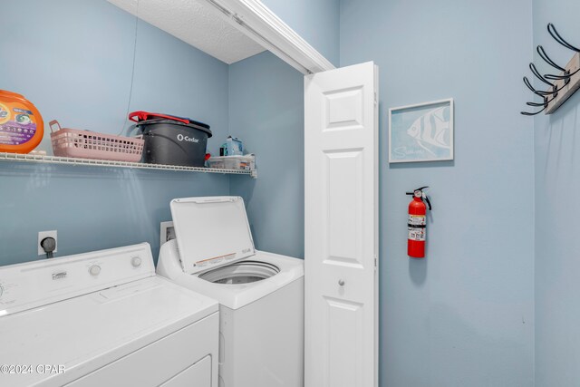 laundry room featuring washer and clothes dryer and a textured ceiling