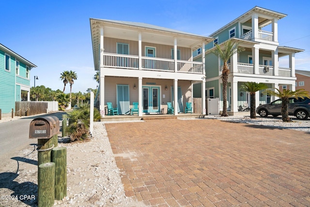 view of front facade featuring french doors, a balcony, and covered porch