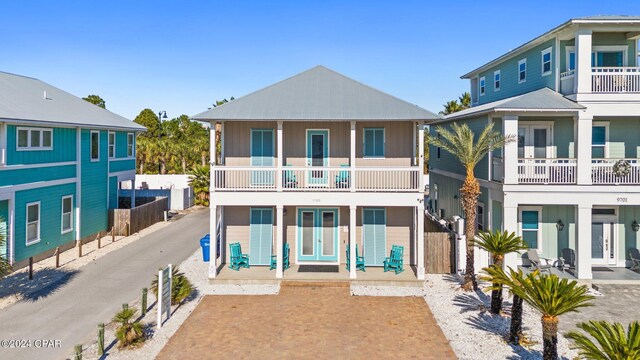 back of property featuring covered porch and a balcony