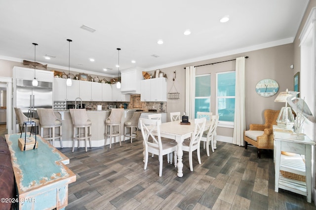 dining area featuring dark hardwood / wood-style flooring, ornamental molding, and sink