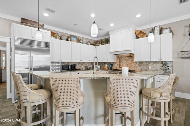 kitchen with white cabinets, a kitchen breakfast bar, dark hardwood / wood-style floors, appliances with stainless steel finishes, and decorative light fixtures