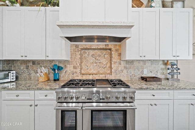 kitchen with decorative backsplash, white cabinetry, and range with two ovens