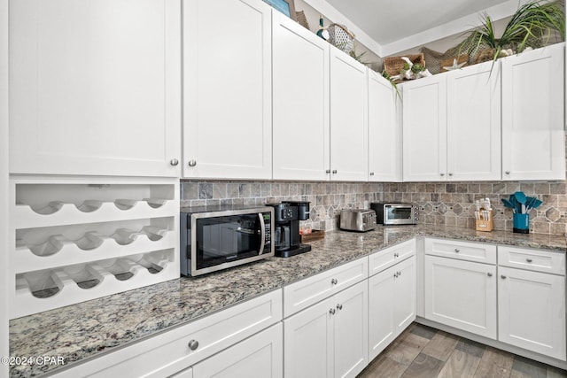 kitchen with white cabinets, backsplash, hardwood / wood-style flooring, and light stone counters