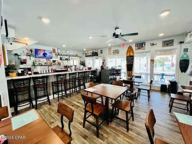 dining space with hardwood / wood-style floors, ceiling fan, and bar