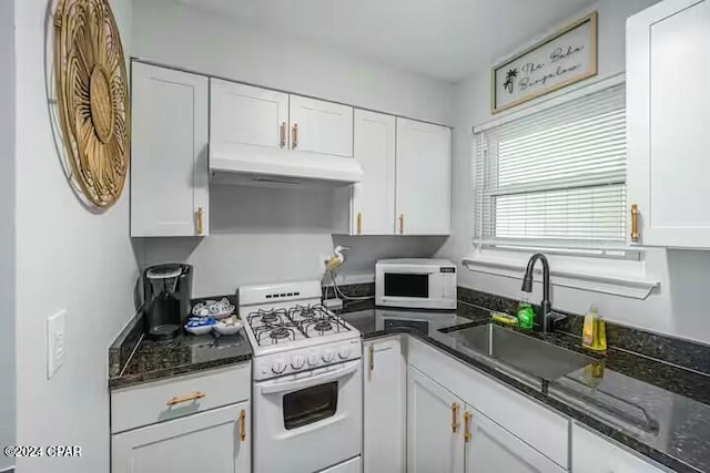 kitchen with white appliances, white cabinetry, dark stone countertops, and sink