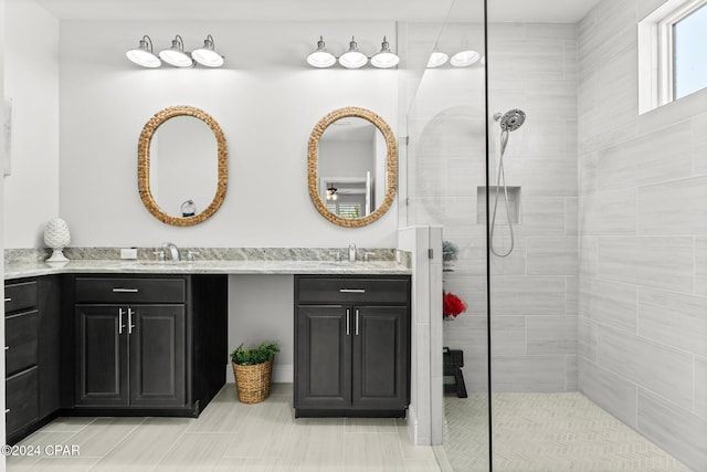 bathroom with tile patterned flooring, a tile shower, and vanity