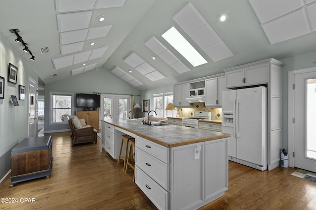 kitchen with white appliances, sink, an island with sink, tile counters, and white cabinetry