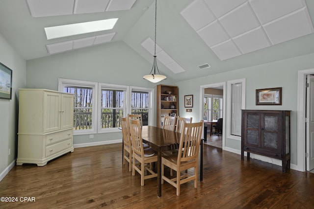 dining space featuring vaulted ceiling with skylight, plenty of natural light, and dark hardwood / wood-style flooring