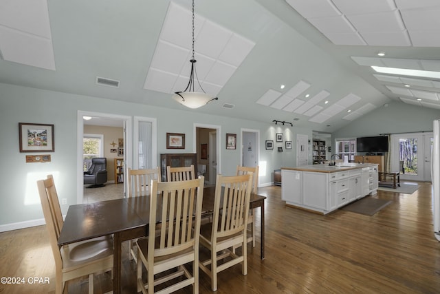 dining space featuring sink, vaulted ceiling, and hardwood / wood-style flooring