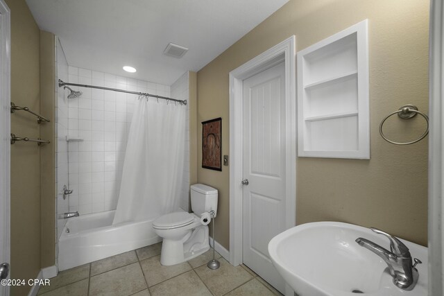 full bathroom featuring tile patterned floors, toilet, shower / bath combo with shower curtain, and sink