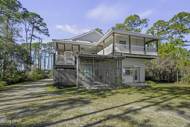 rear view of house with a yard, a sunroom, and a balcony