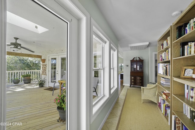 hallway featuring a healthy amount of sunlight, light wood-type flooring, and lofted ceiling with skylight