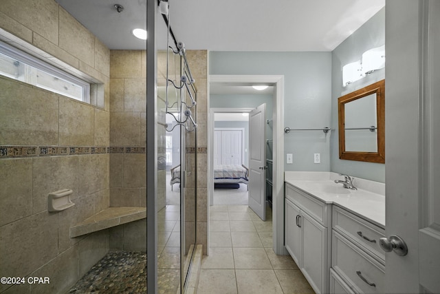 bathroom featuring tile patterned flooring, a tile shower, and vanity