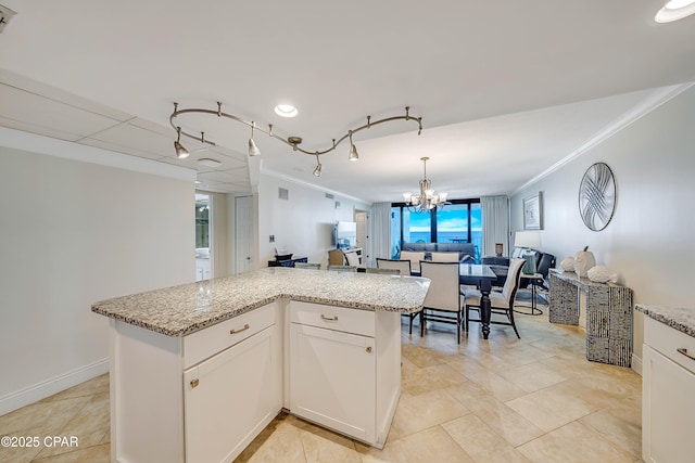 kitchen featuring light stone countertops, an inviting chandelier, open floor plan, and crown molding