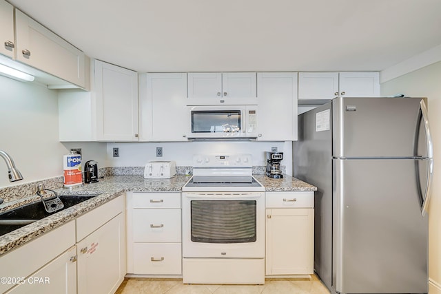 kitchen featuring white appliances, white cabinetry, a sink, and light tile patterned flooring