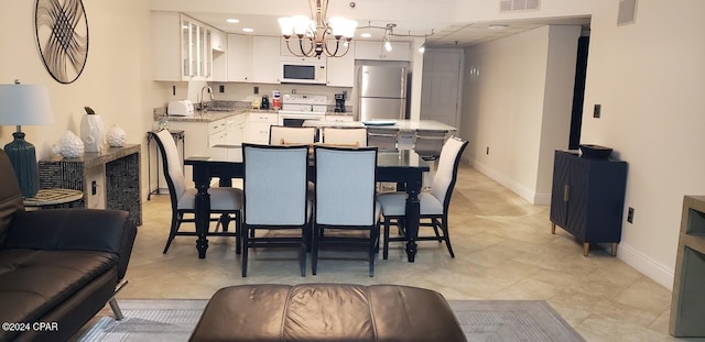 tiled dining room with sink and an inviting chandelier