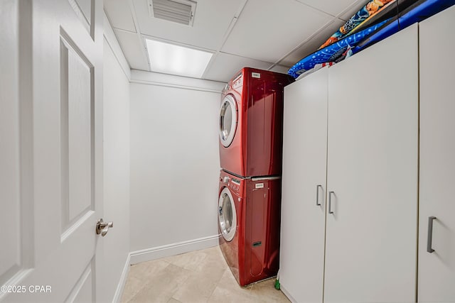 laundry room featuring laundry area, light tile patterned floors, baseboards, visible vents, and stacked washer and clothes dryer